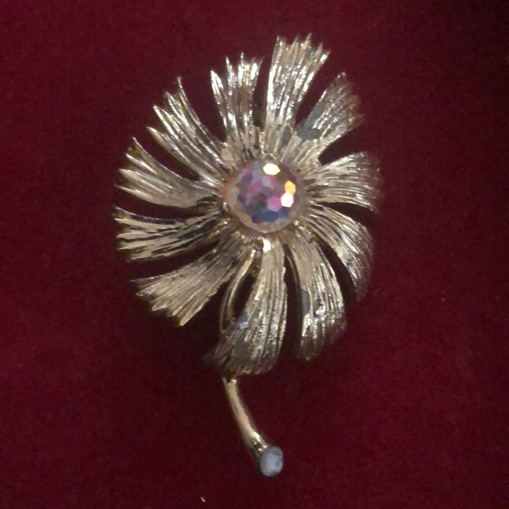 Gold tone flower with aurora stone in the center.